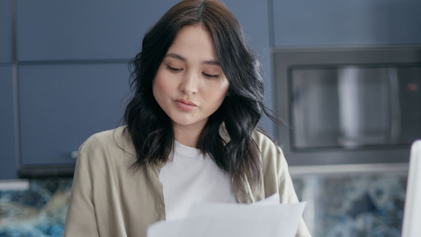 Job applicant reviewing application papers at a kitchen table.