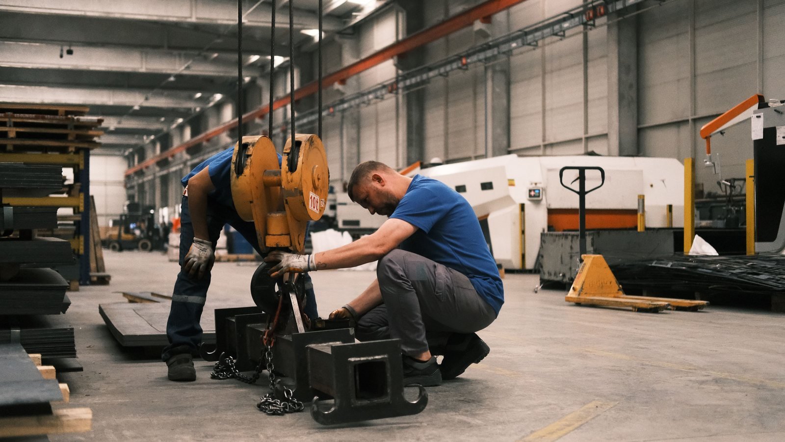 Workers handling equipment together in a manufacturing workplace.