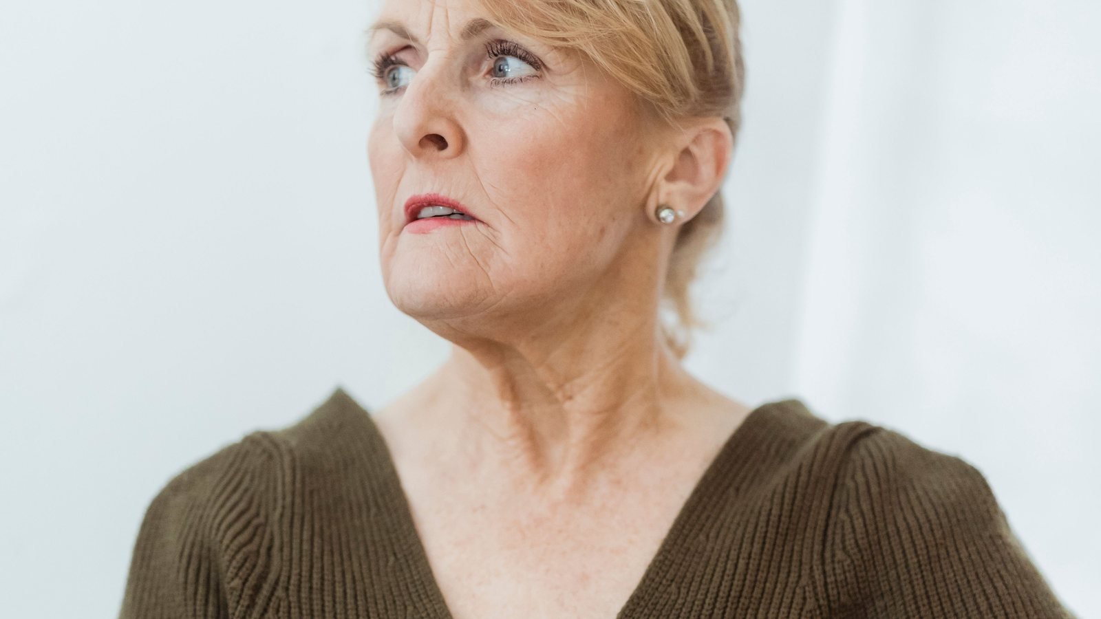 Mature woman thinking carefully while reviewing information on a laptop.