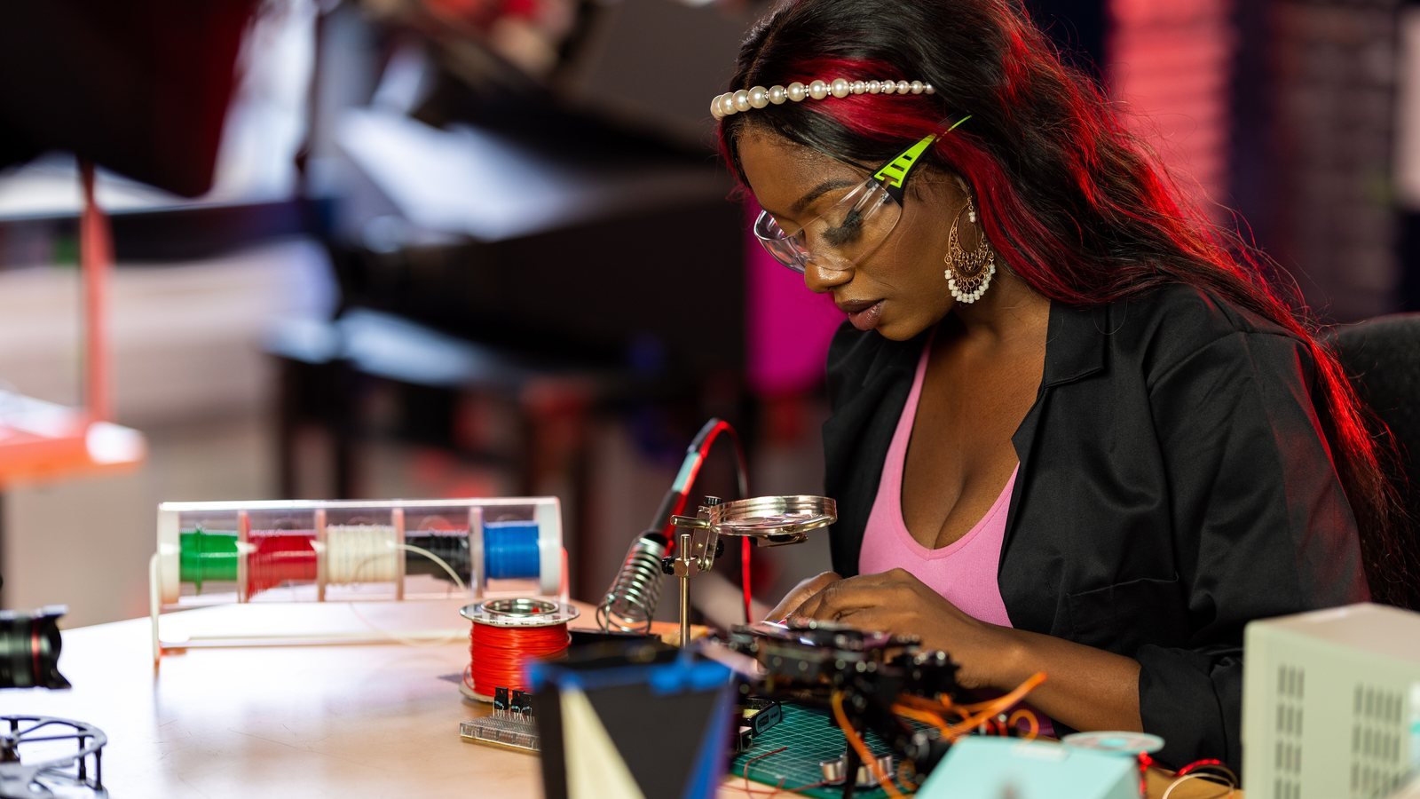 Adult learner practicing an electronics skill at a workbench.